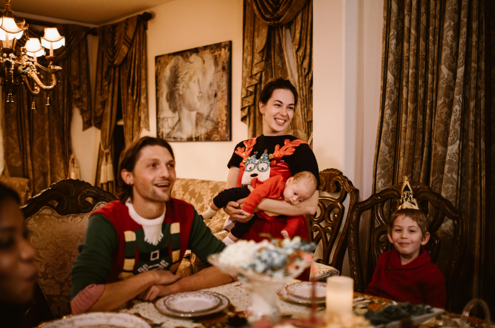 Smiling family gathered around a festive dining table at Christmas, creating a warm, joyful atmosphere that reflects a celebration with non alcoholic Christmas drinks and family-friendly traditions.