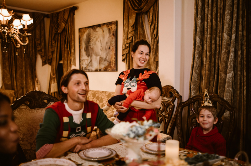 Smiling family gathered around a festive dining table at Christmas, creating a warm, joyful atmosphere that reflects a celebration with non alcoholic Christmas drinks and family-friendly traditions.