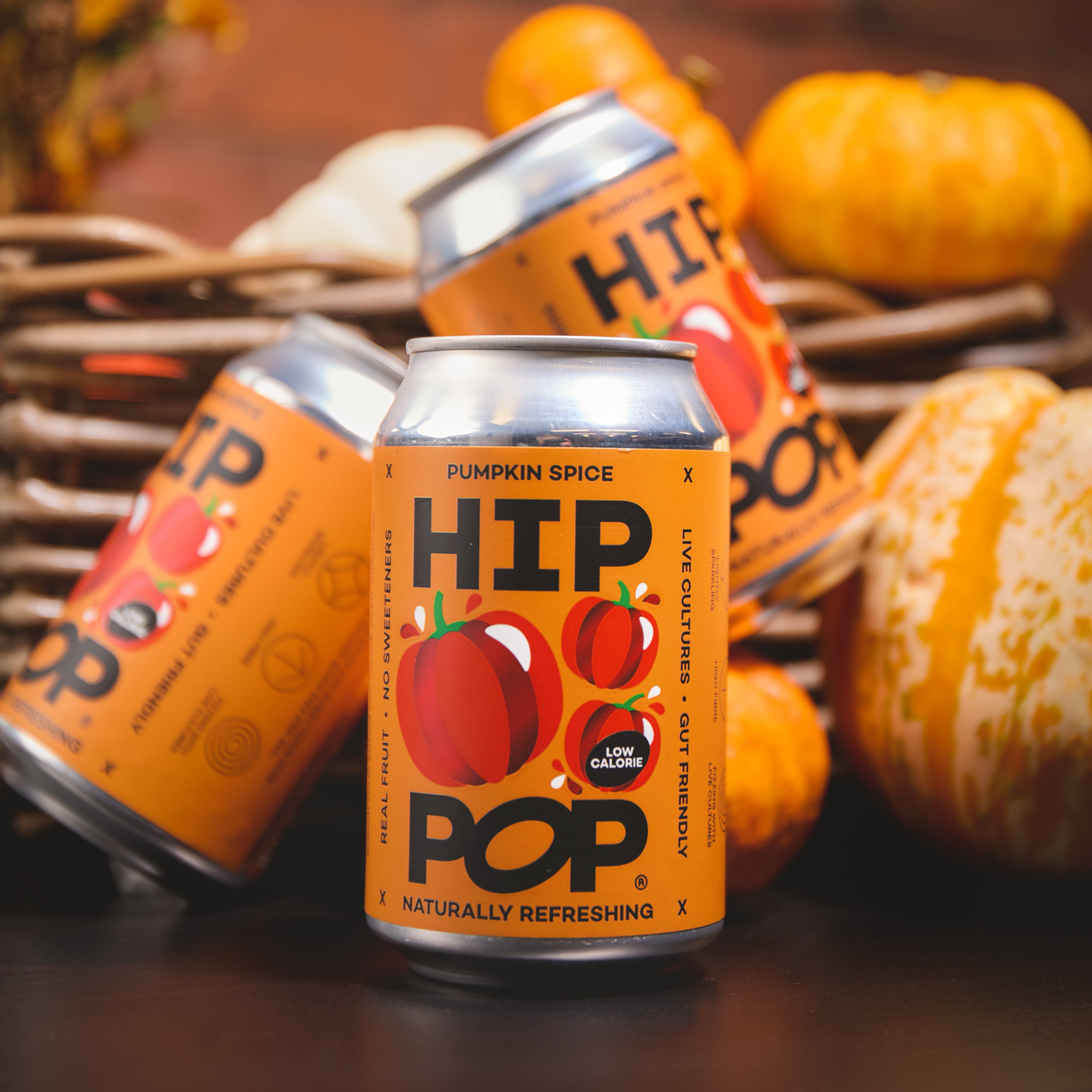 Close-up of HIP POP Pumpkin Spice drink cans arranged with mini pumpkins, highlighting the limited edition autumn flavour.