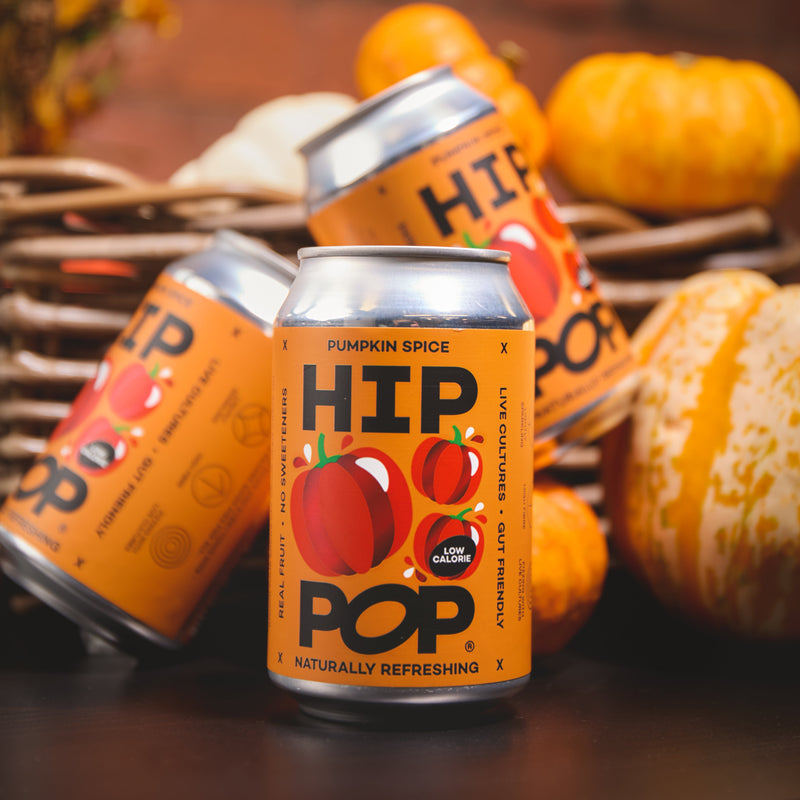 Close-up of HIP POP Pumpkin Spice drink cans arranged with mini pumpkins, highlighting the limited edition autumn flavour.