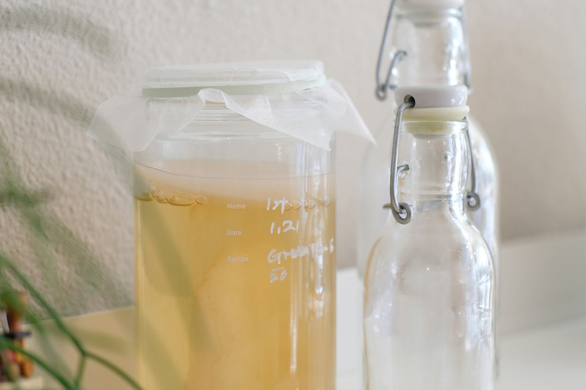 a jar of liquid next to a glass bottle of liquid