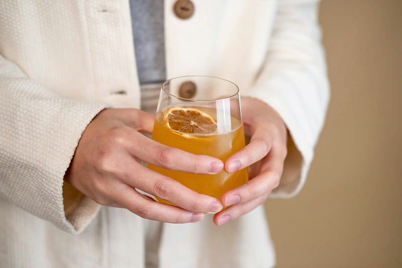photo of person holding glass of kombucha drink