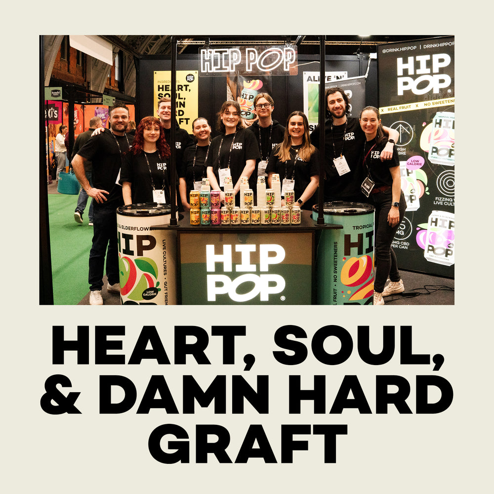 Hip Pop team standing behind a 'HIP POP' branded booth with products on display.