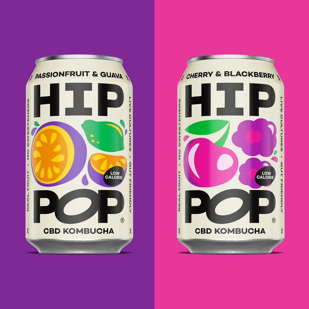 Two cans of HIP POP CBD Kombucha on a two-tone purple and pink background.