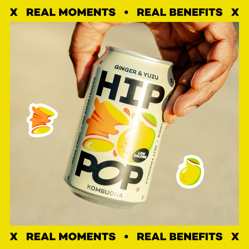 Hand holding a can of HIP Pop Kombucha with yellow border and text.