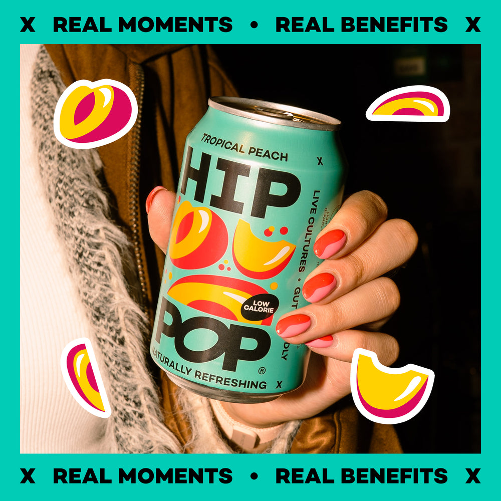 Hand holding a can of HIP Pop Tropical Peach flavor against a teal background with decorative elements.
