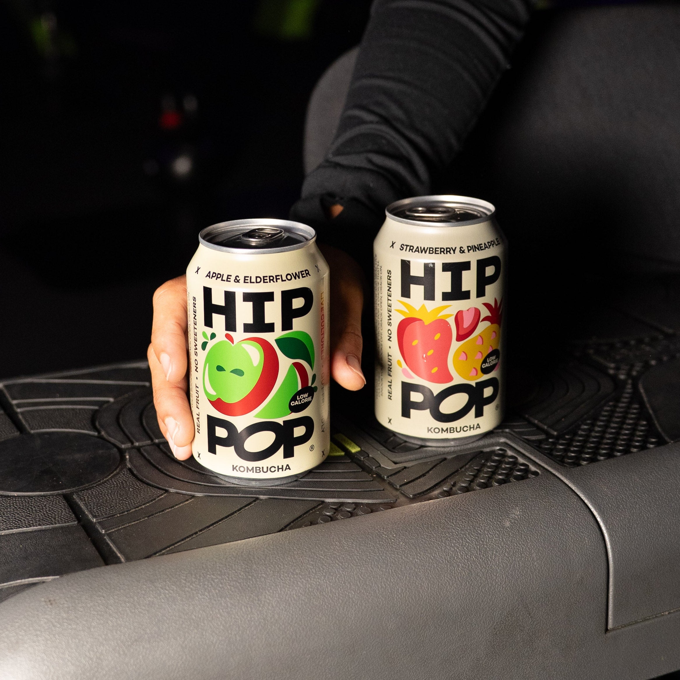 Two cans of 'HIP POP' on a gym machine with a person's hand holding them.